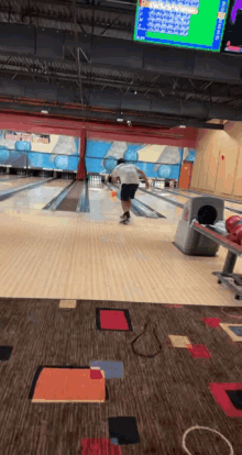 a bowler throws a ball in a bowling alley with a scoreboard behind him that shows a score of 88