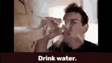 a man is drinking water from a glass with the words drink water written below him