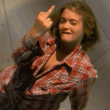 a woman wearing a plaid shirt giving the middle finger