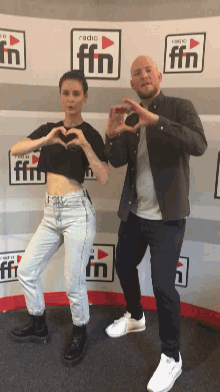 a man and a woman are making hearts with their hands in front of a wall that says radio fm