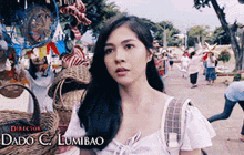 a woman in a white top is standing in front of a sign that says director dado c / lumibao