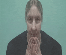 a woman with her hands folded in front of her mouth