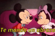 mickey mouse and minnie mouse are standing next to each other on a pink couch .