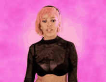 a woman with pink hair is wearing a black bra and a crop top .