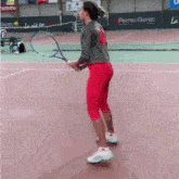 a woman is holding a tennis racquet on a court with a sign that says perros guirec in the background