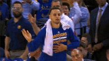 a basketball player with a towel around his neck is standing in front of a crowd at a basketball game .