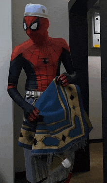 a man in a spider man costume is holding a blue and gold rug