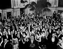 a large group of people dressed in tuxedos are posing for a picture .