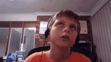 a young boy wearing headphones looks up at the camera