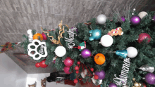 a christmas tree is decorated with purple and white ornaments and a paw print decoration