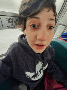 a young boy wearing a black hoodie with a maple leaf on it