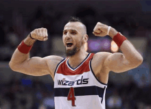 a man in a wizards jersey is flexing his muscles on a basketball court .