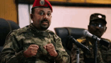 a man in a military uniform is sitting in front of two microphones .