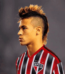 a man with a mohawk is wearing a red and black striped shirt that says spfc