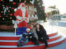 three people sitting in front of a christmas tree with a sign that says onia