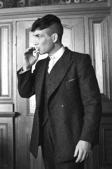 a black and white photo of a man in a suit smoking a cigarette