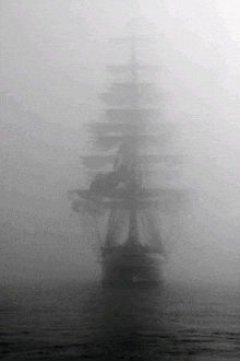 a black and white photo of a ship in the fog