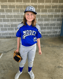 a young girl wearing a model baseball uniform holds a glove