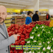 a man standing in front of a display of vegetables with the words on peut meme voyager avec les saveurs