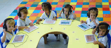 a group of children wearing headphones sit around a table