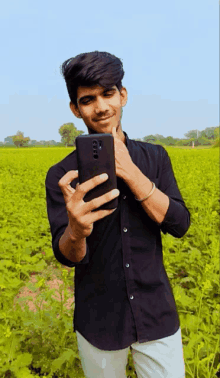 a young man in a black shirt is taking a selfie with his phone