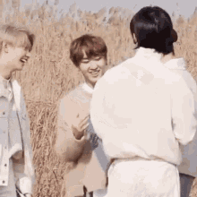 a group of young men are standing in a field laughing and talking .