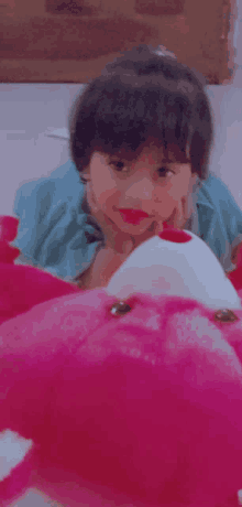 a little girl is laying on the floor with a pink stuffed animal