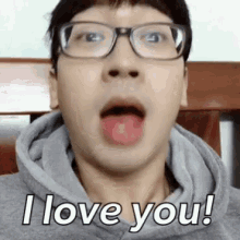 a man wearing glasses and a hoodie is making a funny face while saying `` i love you '' .