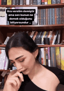 a woman sitting in front of a bookshelf with a caption that says ara verelim demistir ama sen bunun ne