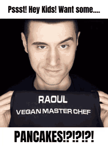 a man holding up a black apron that says raoul vegan master chef