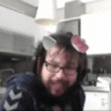 a man with a beard and glasses is sitting in a kitchen with a flower on his head .