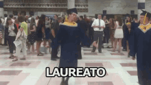 a man in a graduation cap and gown is dancing in front of a crowd with the word laureato written on the floor