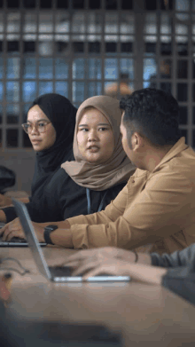 a group of people sit at a table with laptops