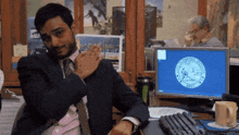 a man in a suit and tie is sitting at a desk in front of a computer screen with the seal of new york on the screen