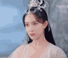 a woman wearing a tiara and earrings is looking at the camera .