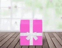 a pink gift box with a white bow on a wooden table .