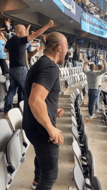 a man in a black shirt stands in a crowded stadium with a banner behind him that says ' lee '