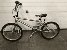 a silver bmx bike is parked against a garage door .