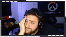 a man wearing headphones in front of a overwatch banner