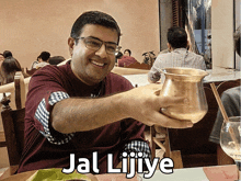 a man holds up a copper pitcher with the words " jal lijiye " written on it