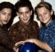 three young men are posing for a picture with one holding a bowling ball