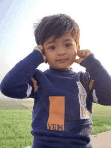 a young boy wearing a blue sweater with yum on it