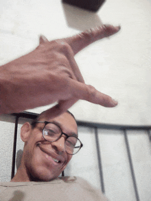 a man with glasses is smiling and pointing his finger