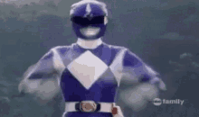 a blue power ranger is flying through the air with his arms in the air .