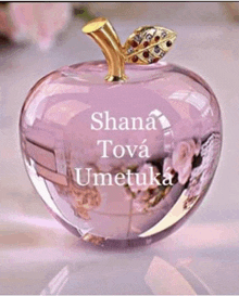 a pink glass apple with the name shana tova umetuka on it