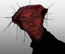 a close up of a person 's face with a red crown of thorns on their head .