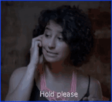 a woman with curly hair is talking on a cell phone and the words hold please are above her