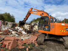 a doosan excavator is destroying a building