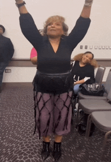 a woman in a black top and purple skirt is dancing