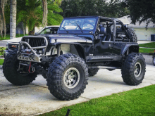 a black jeep is parked in a driveway next to a gmc truck